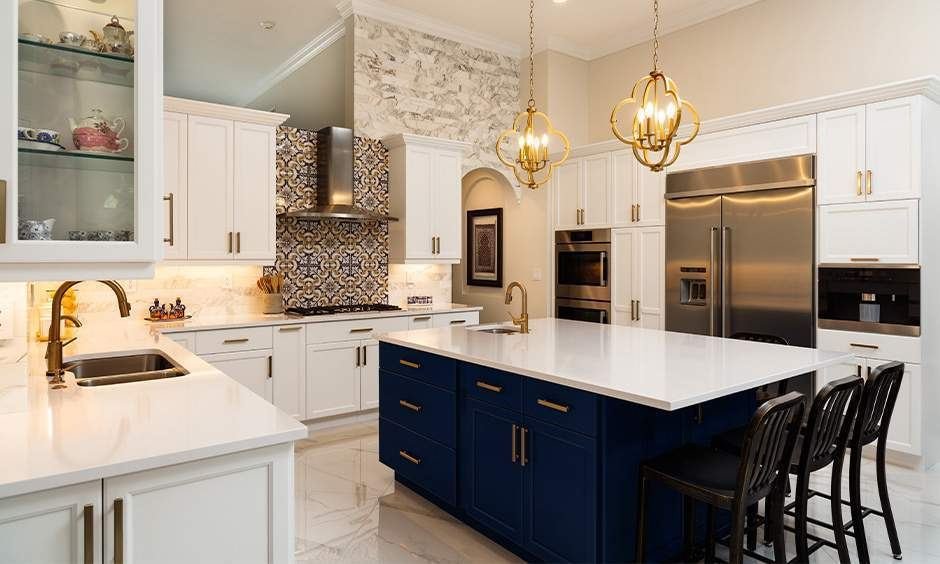 Modular kitchen with white cabinetry, navy island, gold fittings and patterned backsplash